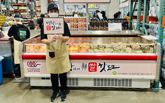 Salesperson-Holding-Sign in Korean in front of refrigerated case 
