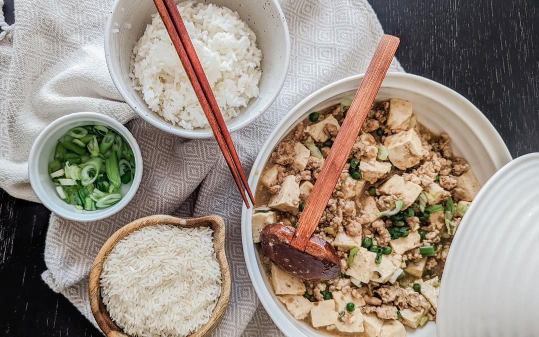 Natalie-Ho-Recipe, Mapo Tofu ingredients displayed on dark surface, bowls of raw and cooked rice, green onions sitting dish towel