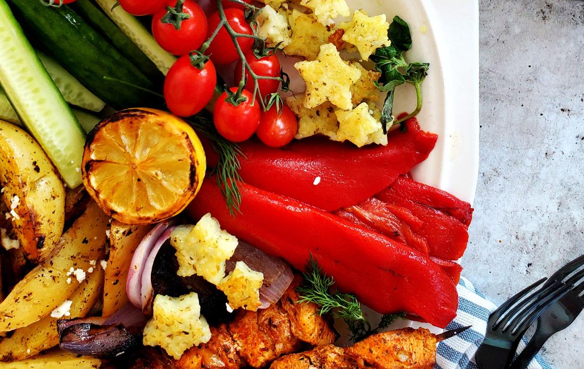 Star-shaped rice croutons in white bowl with red tomatoes and peppers, squash, chicken, lemons with a bowl of raw rice on the side