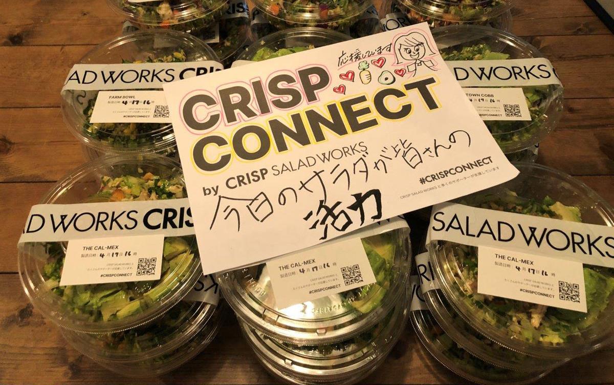 Salads in clear plastic to-go containers stacked on table under sign that reads:  Crisp Connect