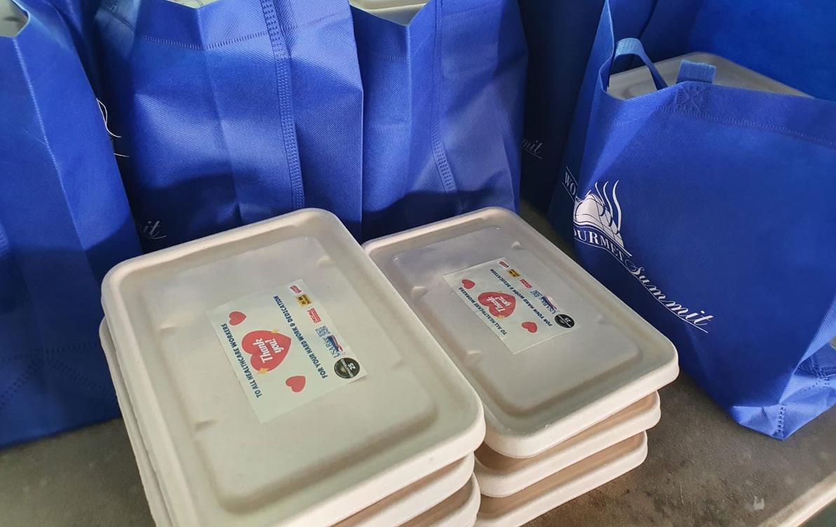 Stacks of containers of meals-for-healthcare-workers in Singapore, blue bags on table