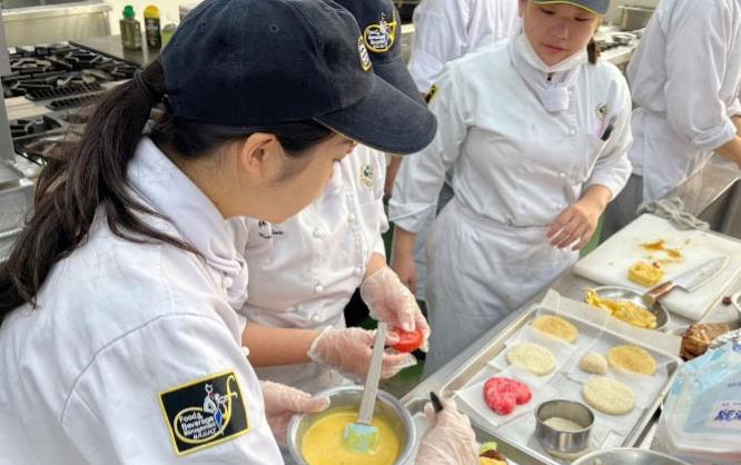 Student chefs in kitchen cooking with ingredients set out on trays