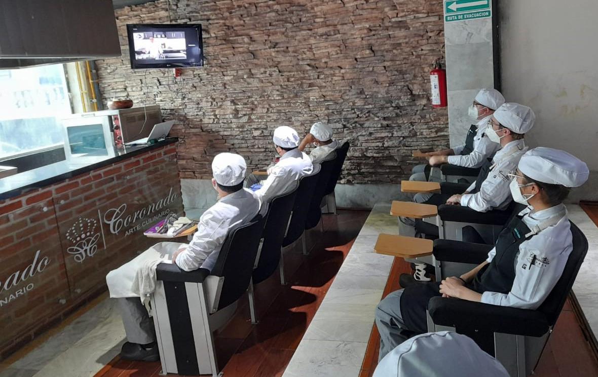 Student chefs seated at desks watch video monitor at chef workshop in Mexico