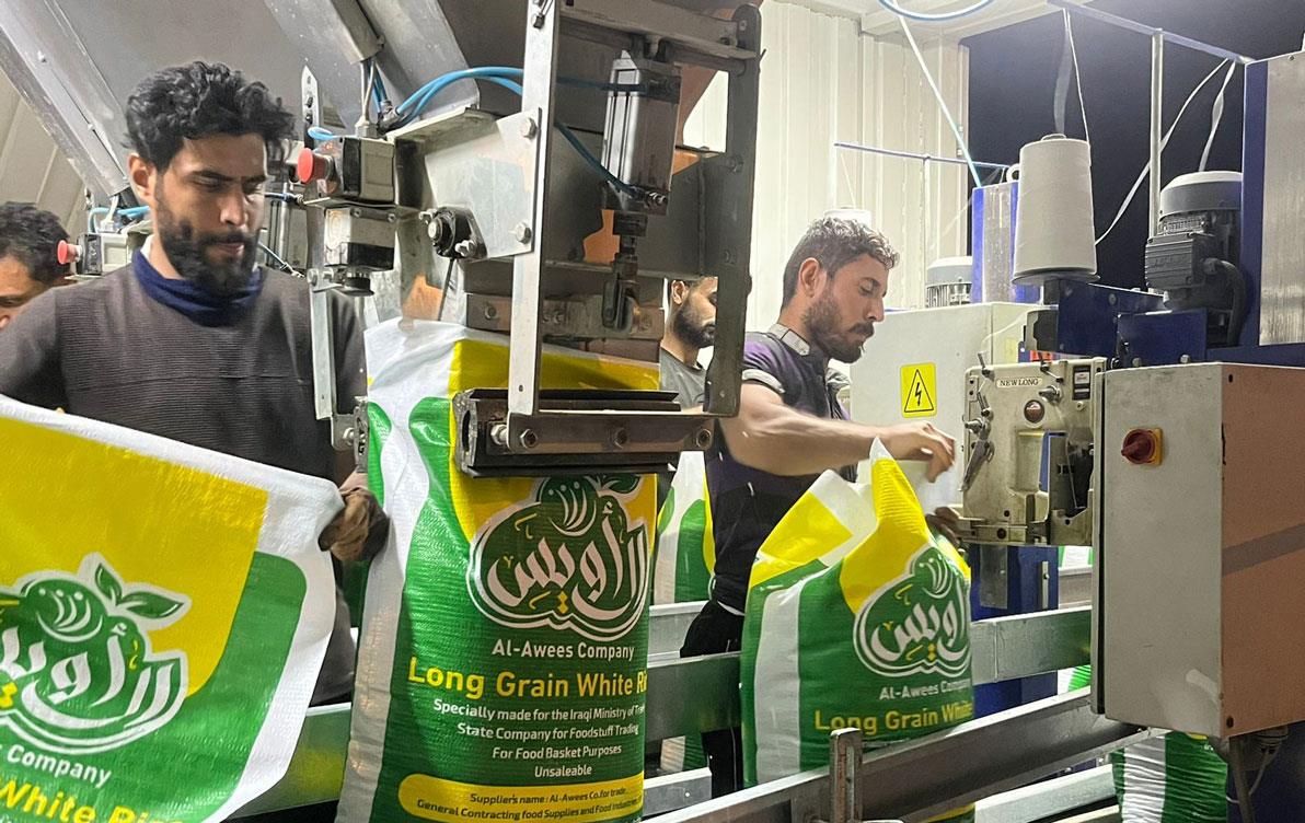 Men work at bagging bulk rice at packaging facility in Iraq