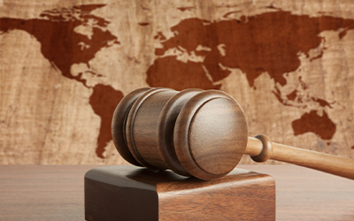 Gavel resting on wood block with world map in background