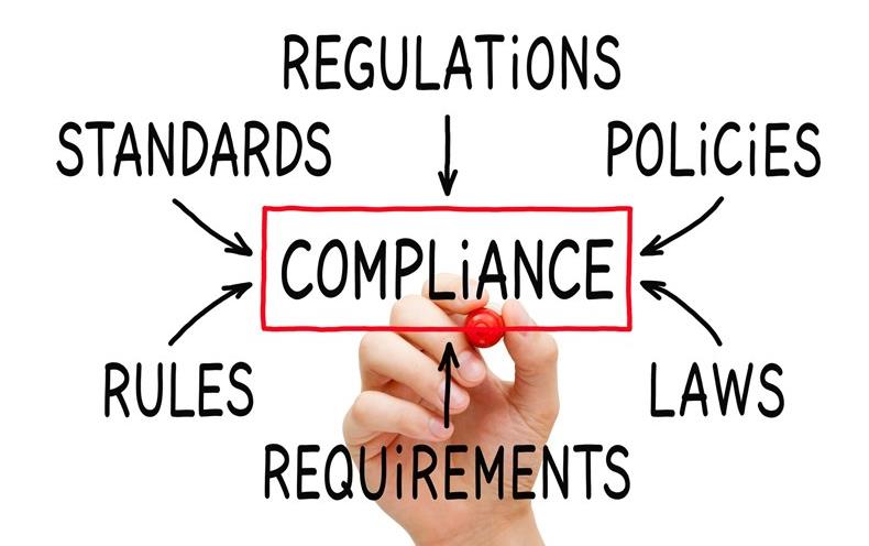 Hand holding red pen writes elements of compliance