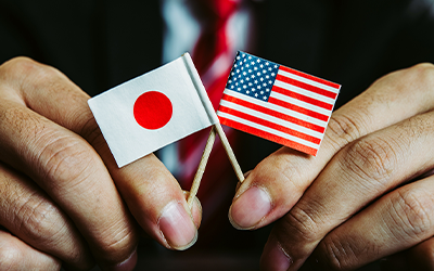 Hands holding Japan & US small paper flags
