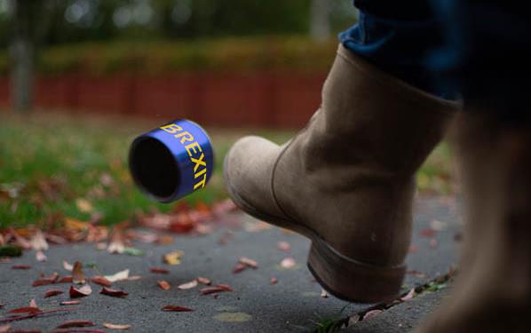 Boot kicking can that says "Brexit" down a leaf-strewn road
