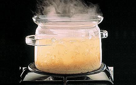 Glass pot of rice boiling on stove top burner