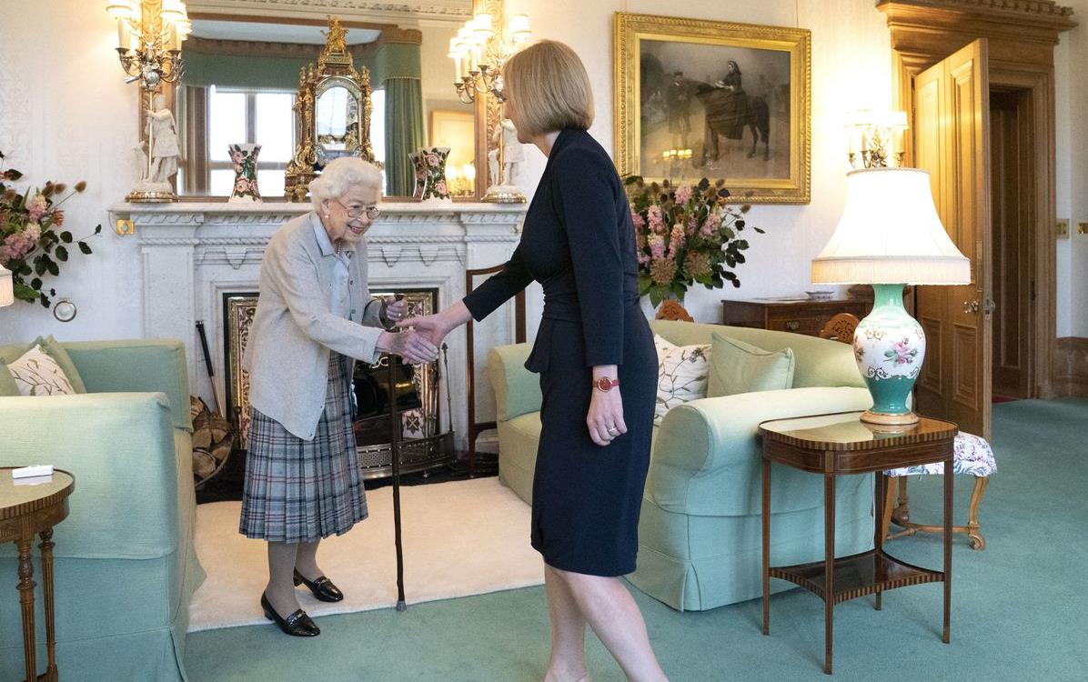 Queen Elizabeth & UK PM Truss shake hands in front of fireplace in an ornate sitting room, Jane Barlow photo Getty Images