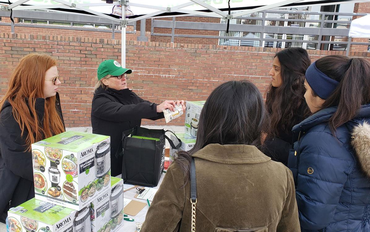 Two women at swag table showing consumers the GITUSA label on a bag of rice