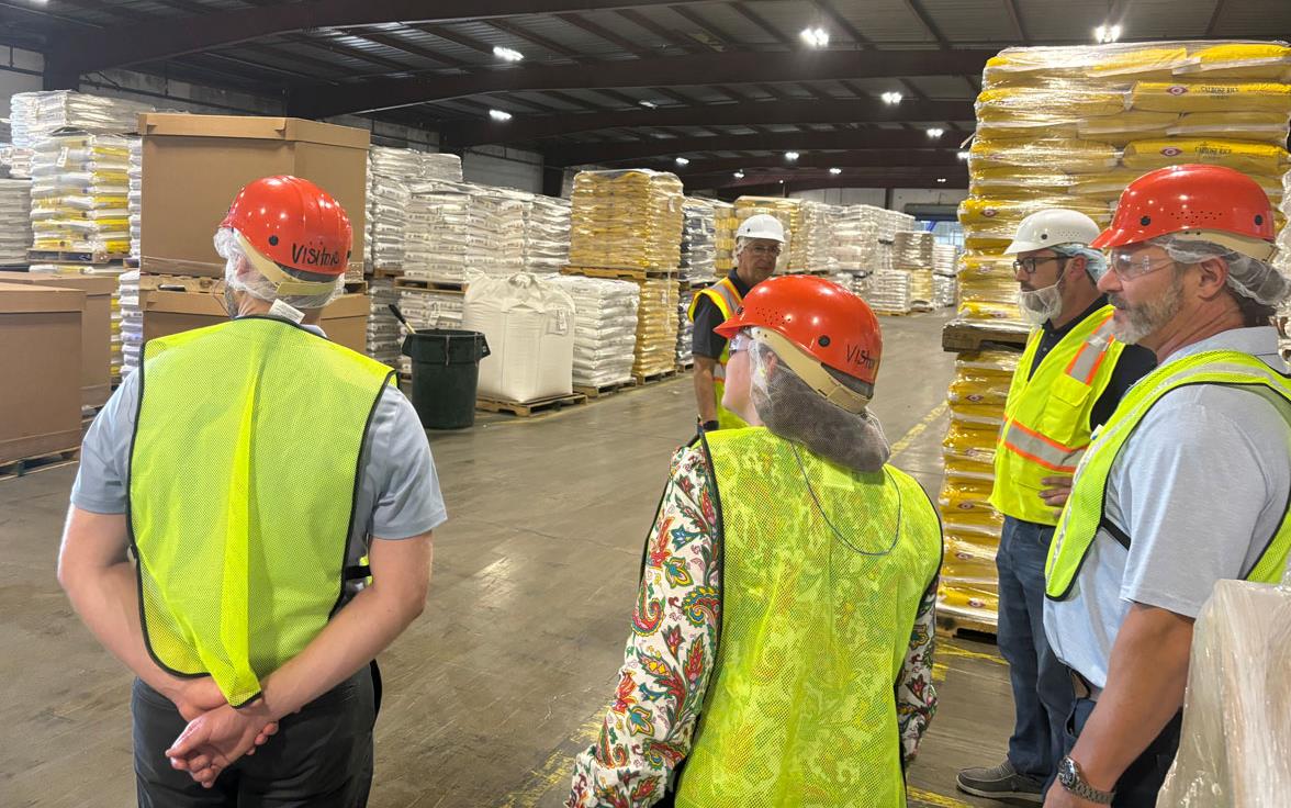 USITC-Tour-of-FRC, people wearing yellow safety vests & hard hats tour rice storage facility