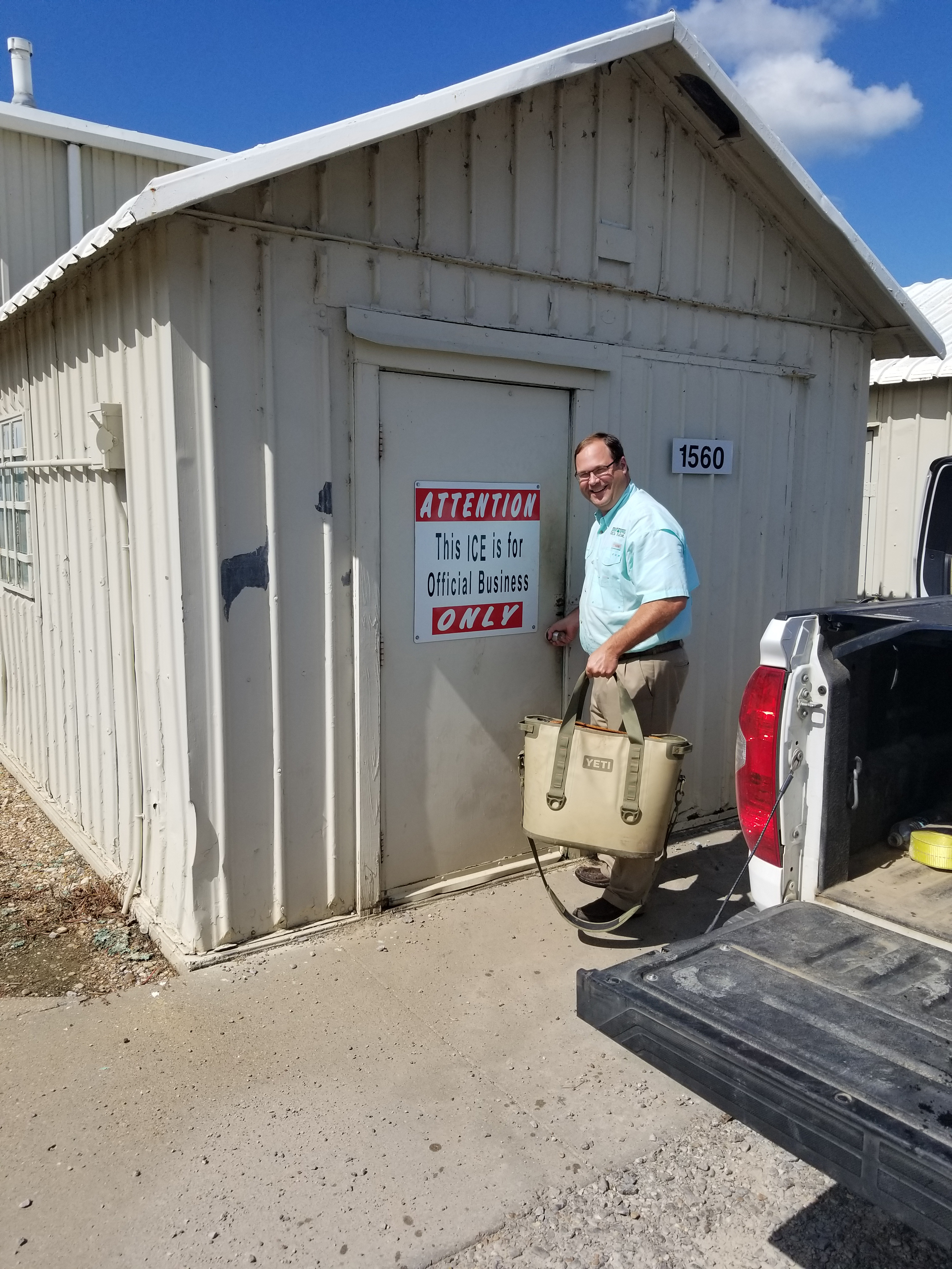 Trey Cooke opens door to an ice shed, carrying a Yeti cooler