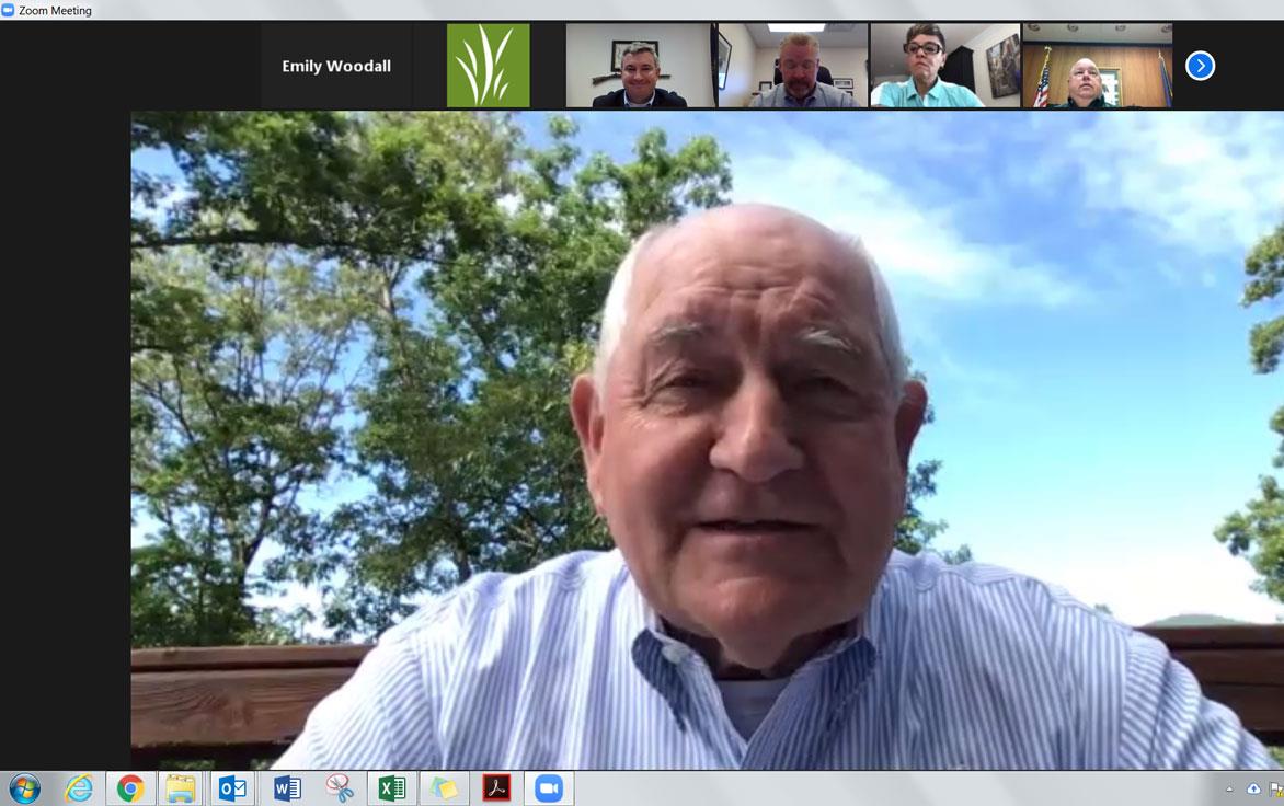 Zoom meeting screenshot shows large picture of older white man with smaller photos of more white people across the top of the screen