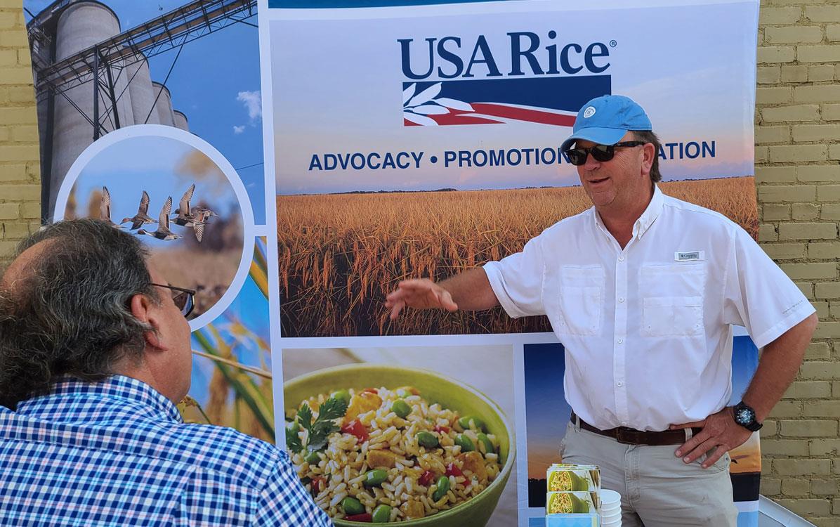 2022-Delta-Rice-Festival, man stands in front of USA Rice booth talking to another man