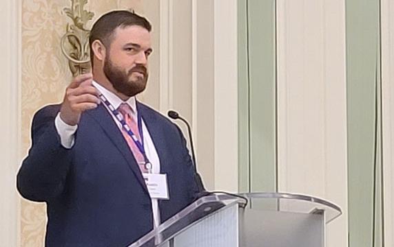 White man wearing business suit stands at podium