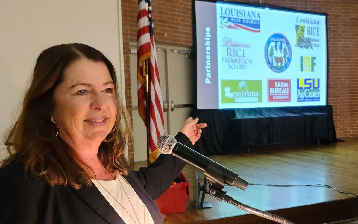 USAR CEO Betsy Ward at dais pointing at presentation screen on stage