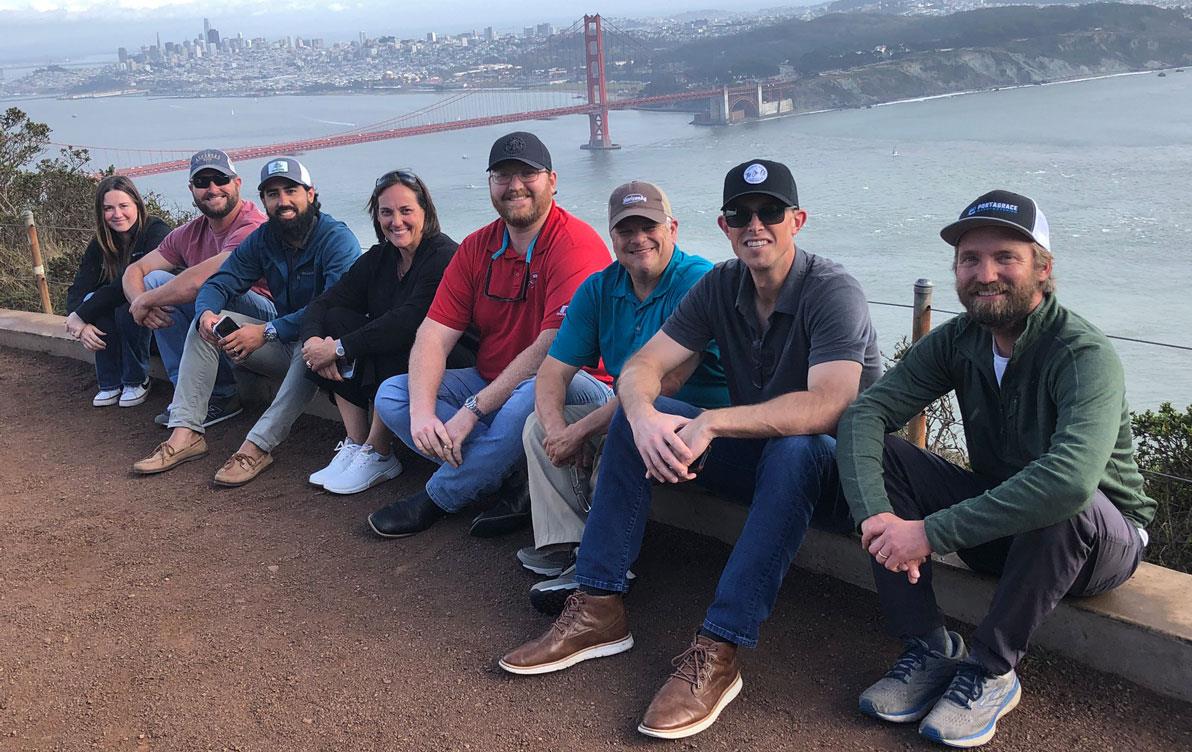 CA-Leadership-Session, group shot of people sitting on curb with Golden-Gate-Bridge in background