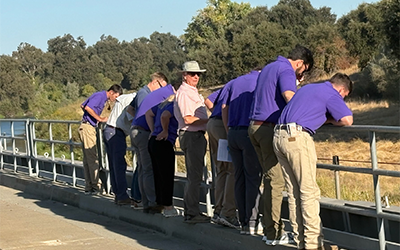 CA Leadership Session, group bending over metal railing observing fish screens