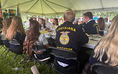 Students sitting at tables under a tent at LA 4H & FFA Capitol Day