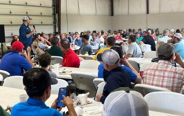 Josh Hankins speaks to crowd gathered indoors at MO Field Day