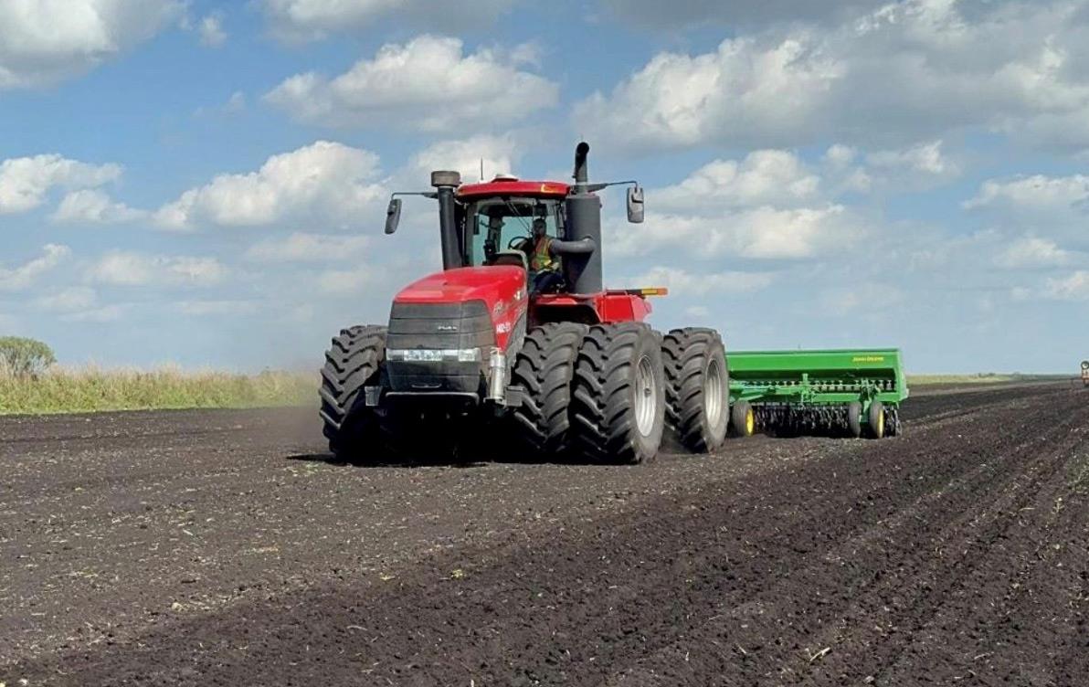 Rice farming in Florida, combine in black dirt field with billowy clouds overhead 