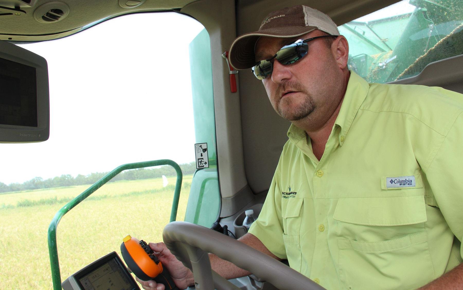 Man wearing yellow shirt and sunglasses drives green combine