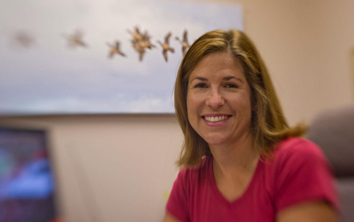 Woman with shoulder-length brown hair smiles at camera