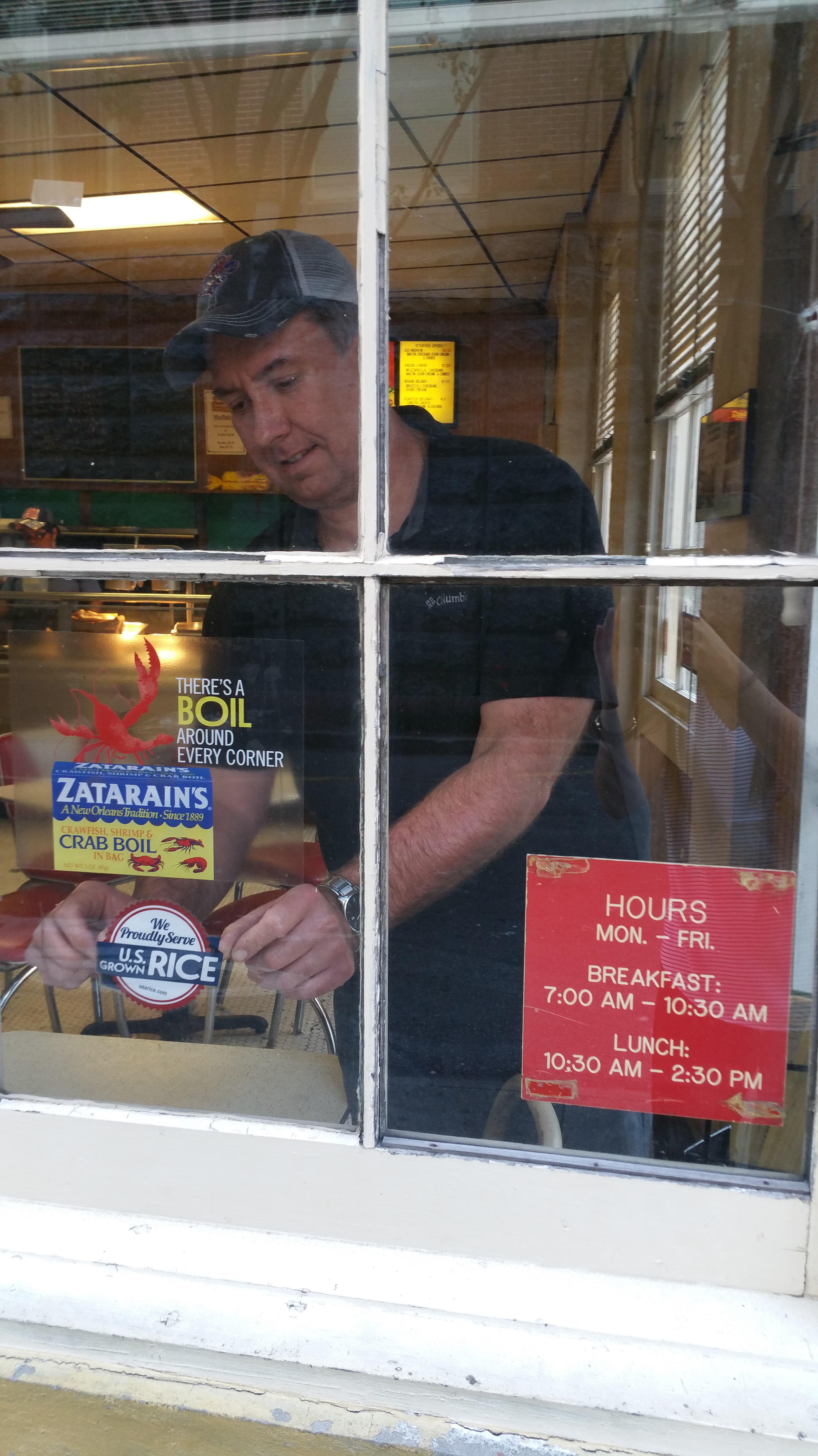 Man places Rice Pride sticker on restaurant window
