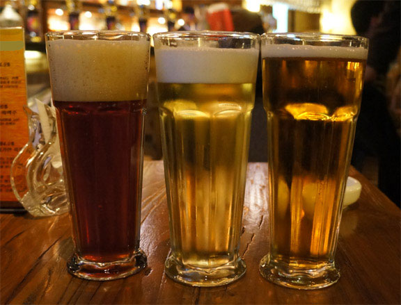 Bird-Friendly-Beer, three full glasses of beer on a bar