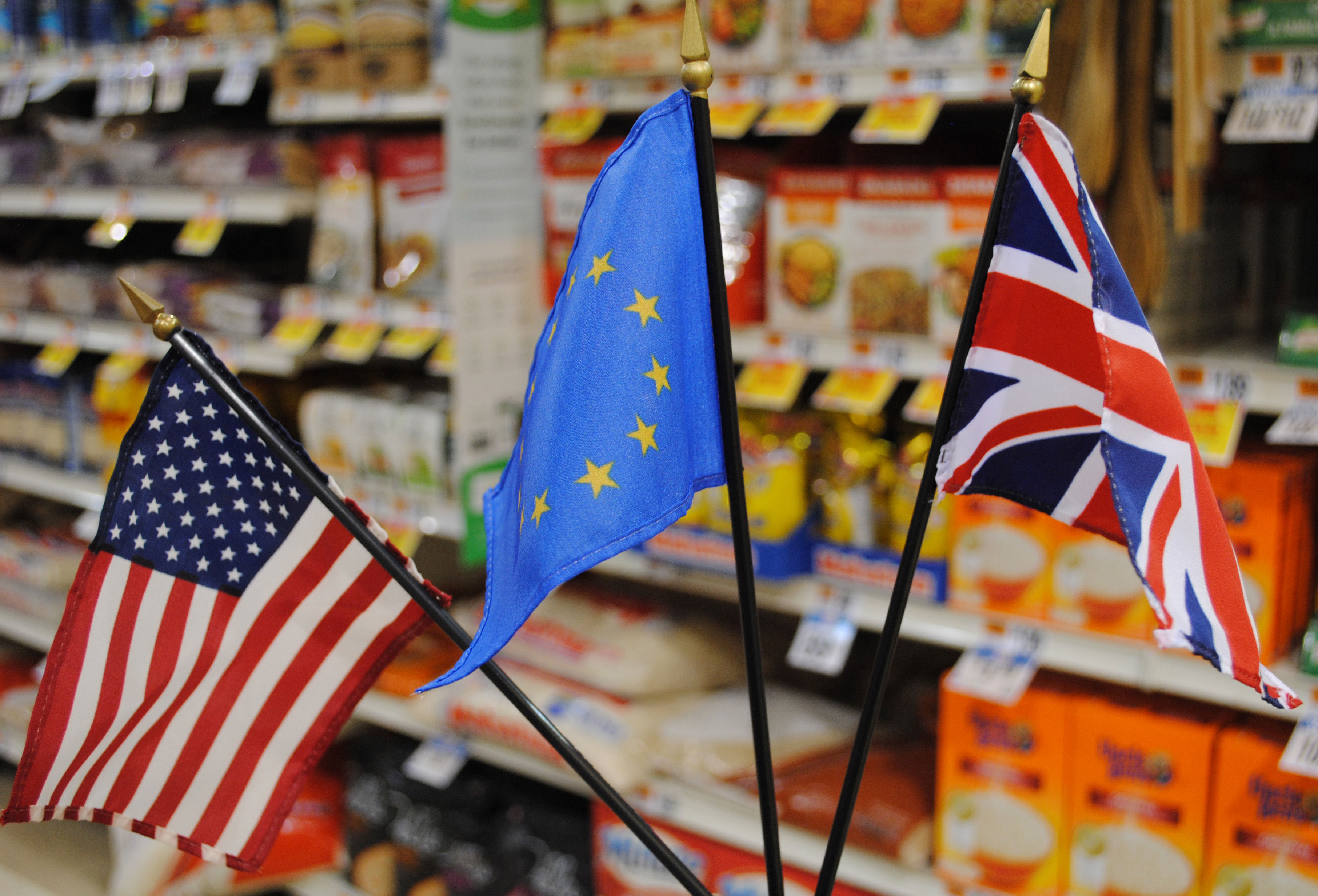 Image of three flags - U.S., EU & UK - in front of supermarket rice aisle
