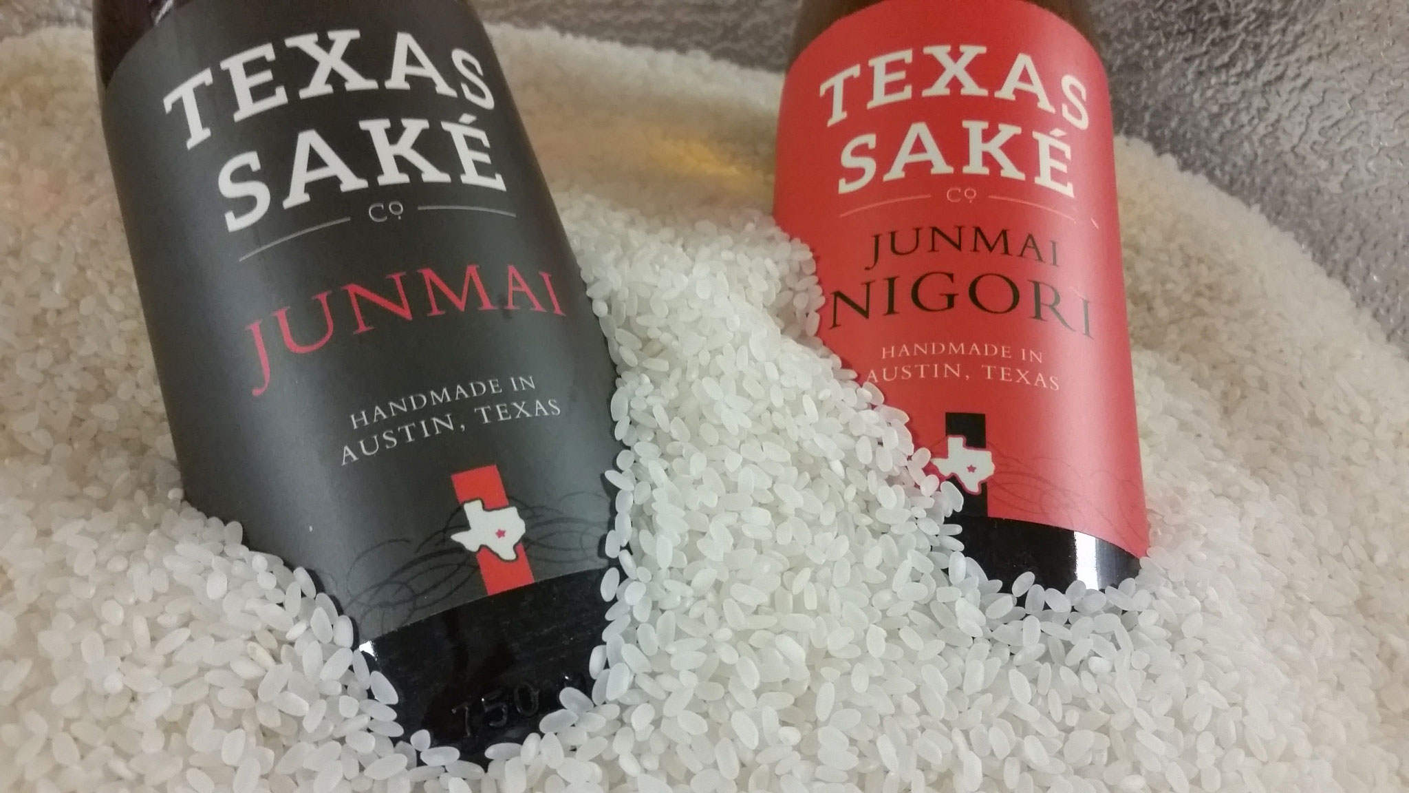 Two bottles of sake surrounded by a pile of white rice