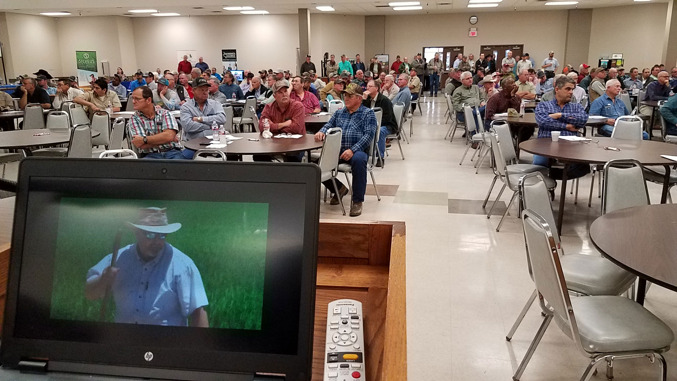 TX-Rice-Conference-meeting, people sitting at tables watching a rice production video