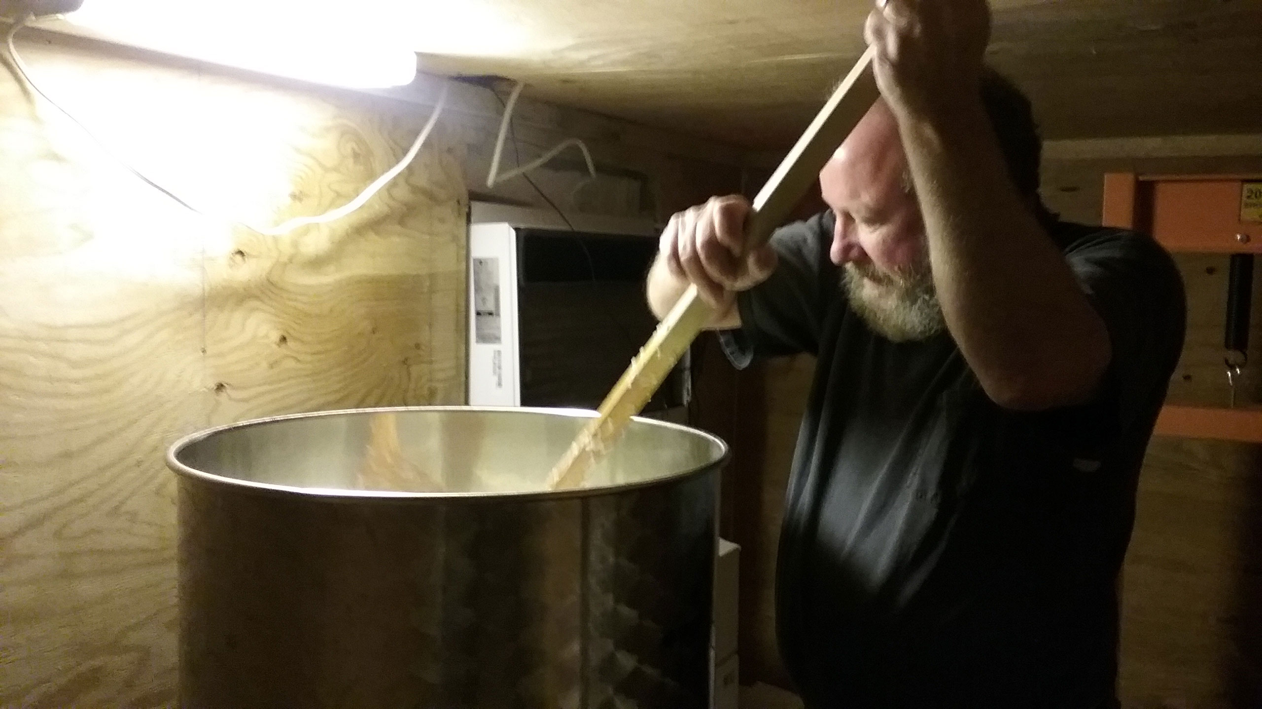Man brewing sake, stirring large pot
