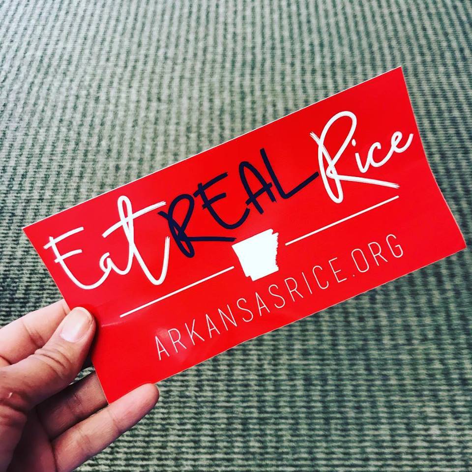 Hand holds red bumper sticker that says: Eat Real Rice, Arkansasrice.org