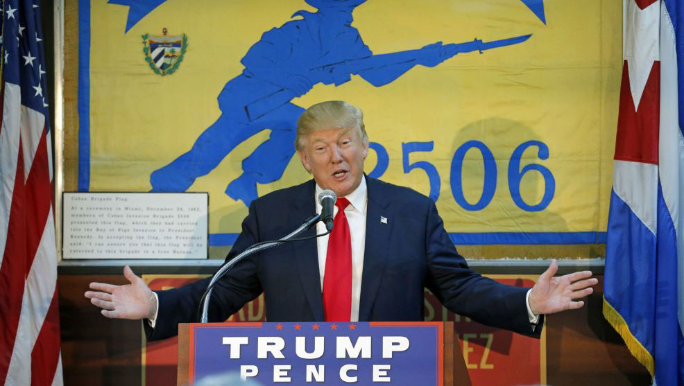 Trump-in-Cuba-standing in front of podium with Trump/Pence sign