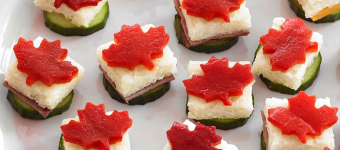 Plate full of bite-sized snacks made with cucumber, rice & red pepper cut in shape of Canadian maple leaf