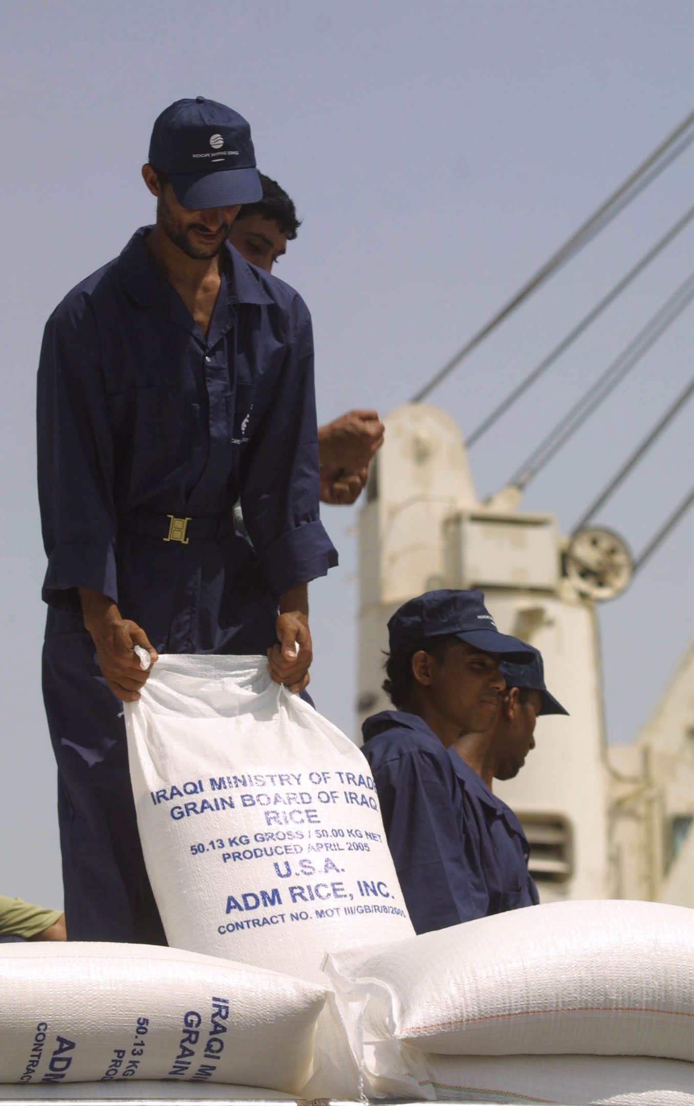 Iraqi Board of Grain employee on a ship holds bag of US Rice