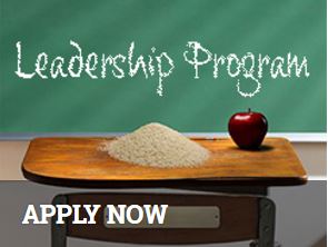 Old fashioned school desk with rice & an apple, Leadership Program written on chalkboard