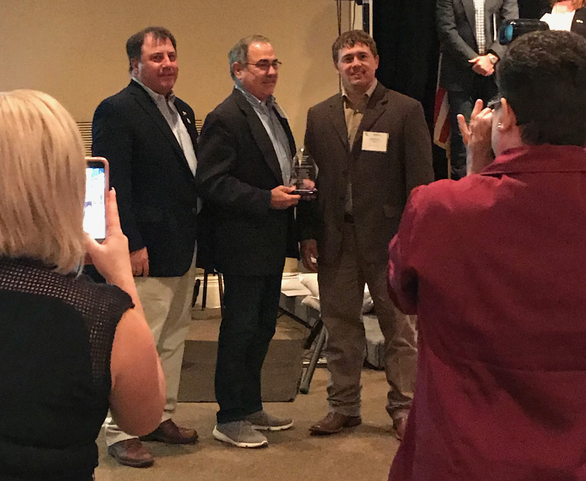 Randy Jemison receives service award while audience takes photos