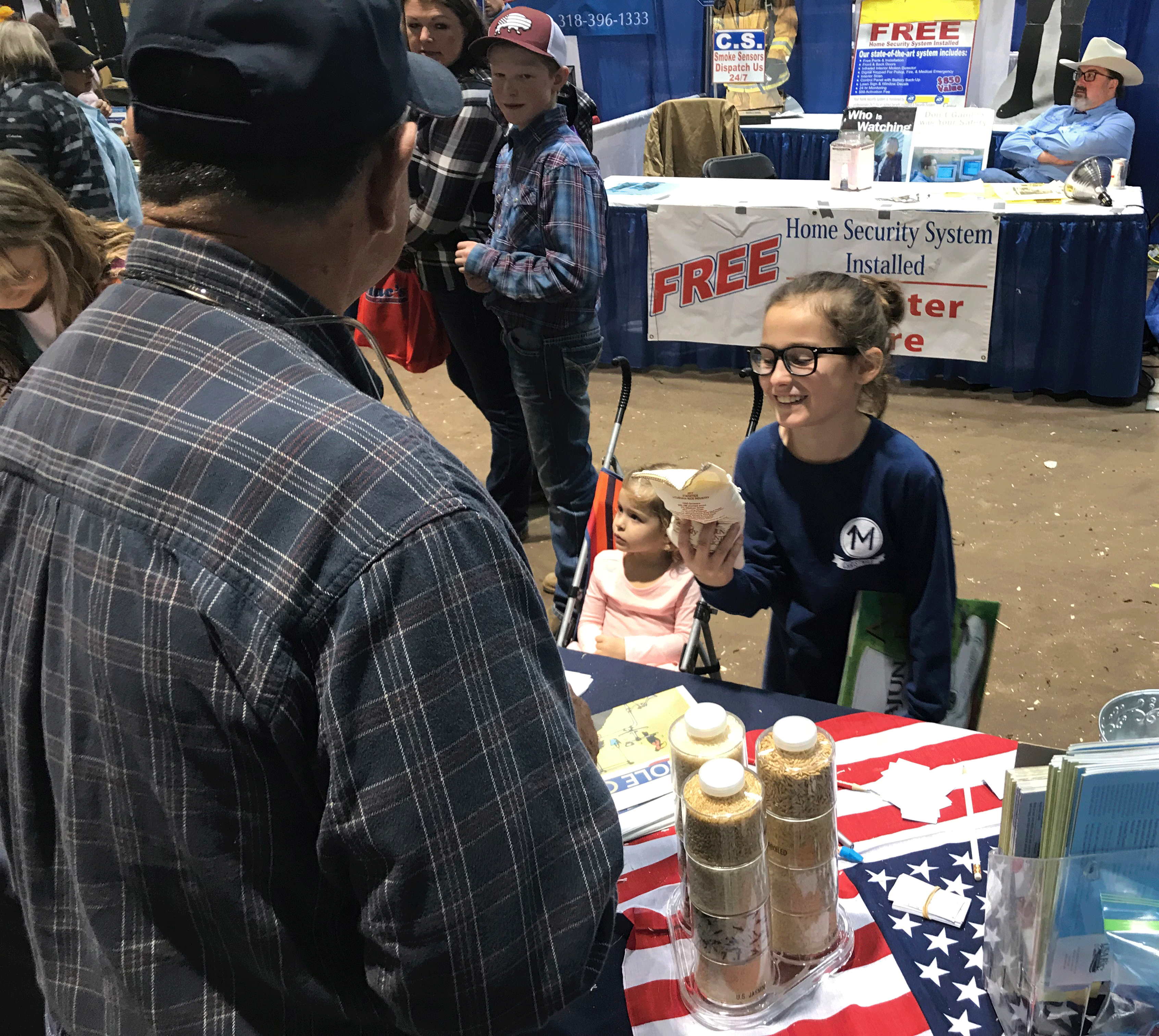 Young girl at trade show booth holds one-lb bag of rice & coloring book
