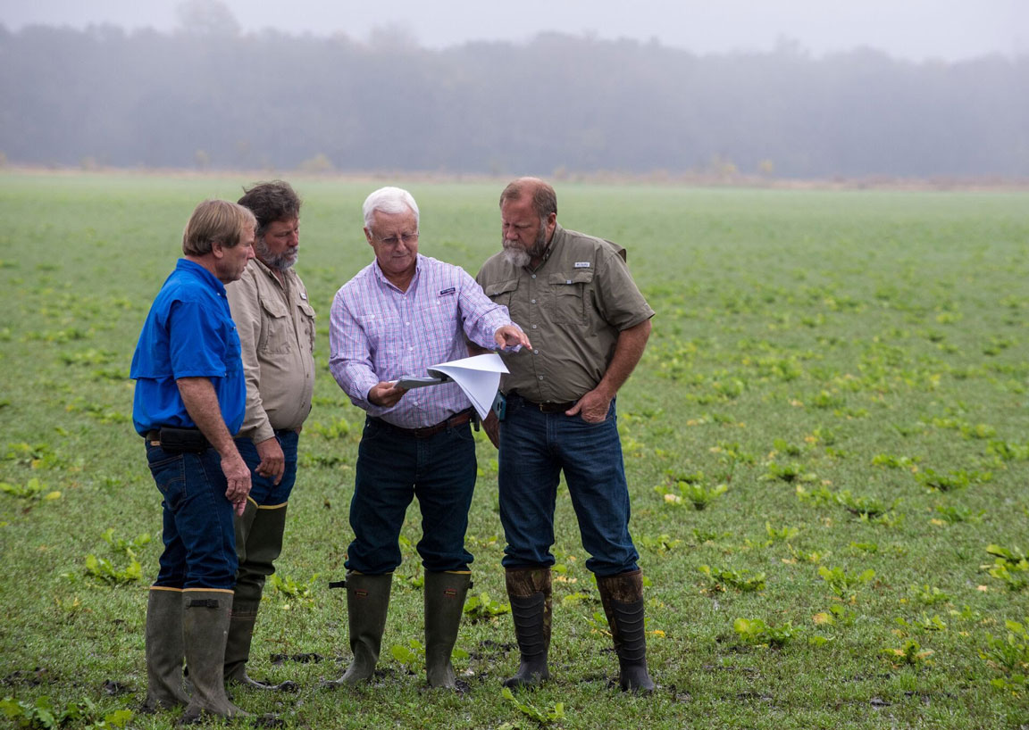 Durands-Honored-for-4R-Stewardship, standing in field looking a man holding soil charts