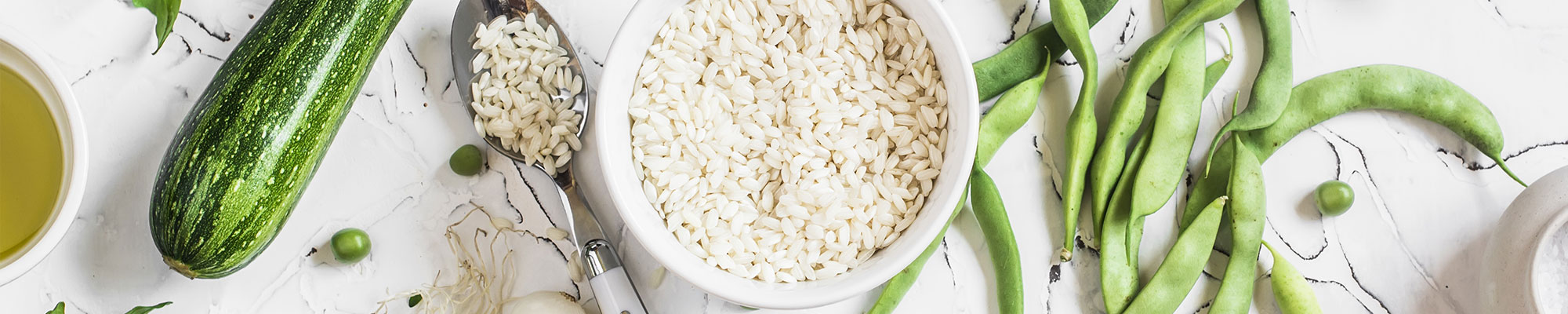 rice-and-vegetables Overhead view of raw rice grains in a bowl surrounded by vegetables.